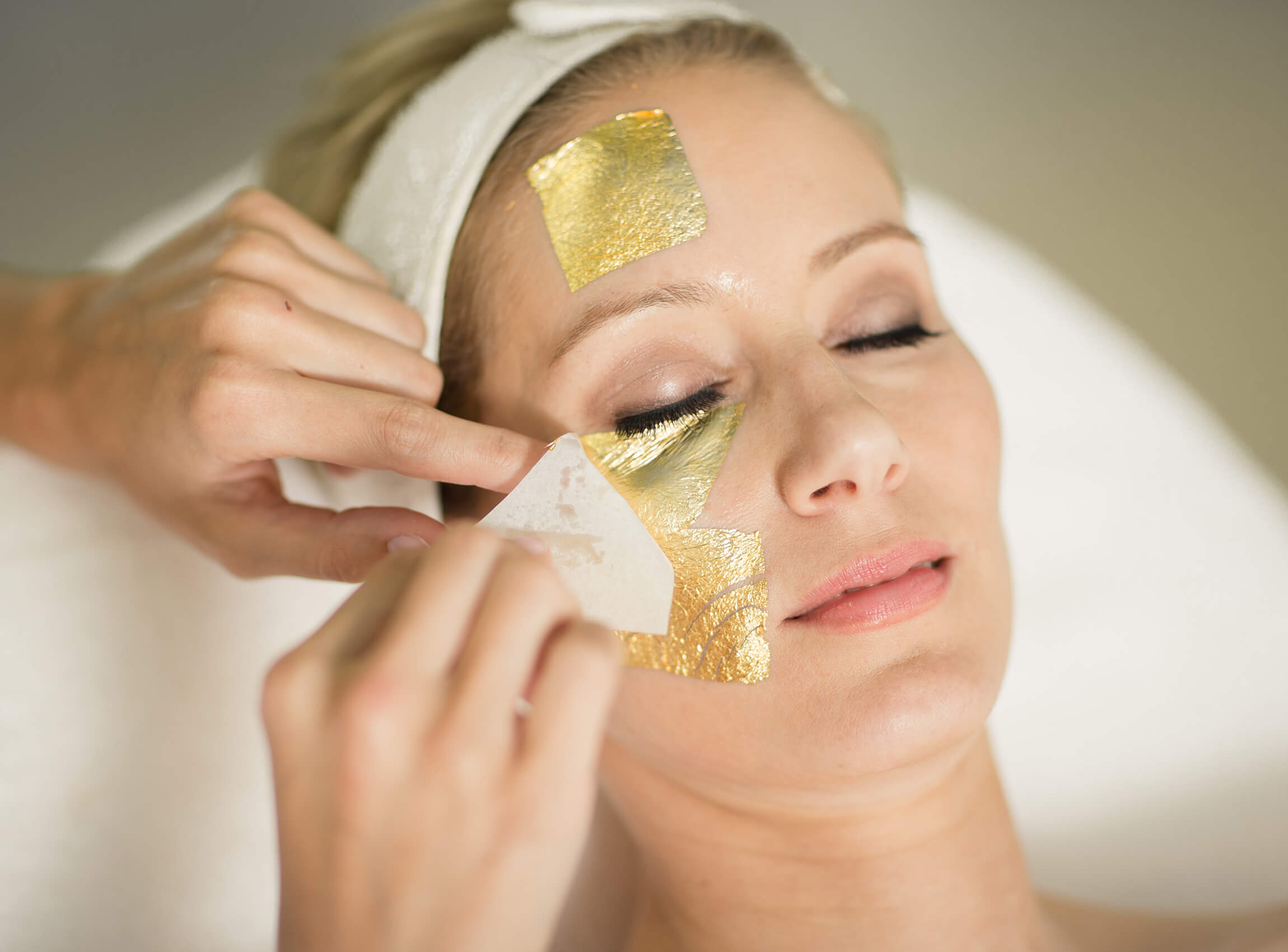 Frau mit einer Gesichtsmaske aus Gold in einem Kosmetikinstitut